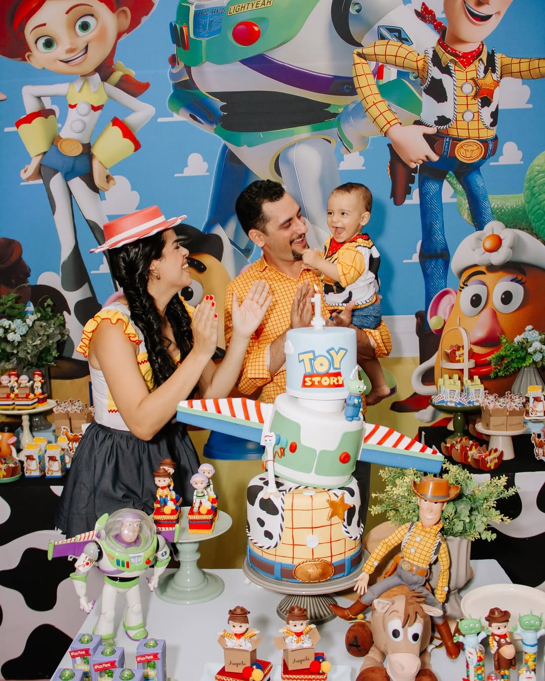 Pais comemorando com o filho no primeiro aniversário com tema Toy Story