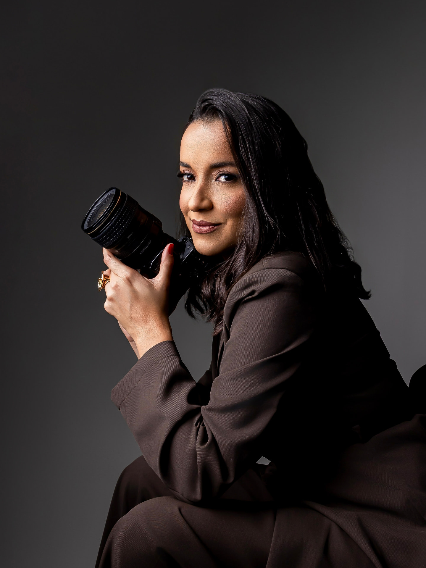 Retrato corporativo de fotógrafa com câmera em estúdio de fundo escuro